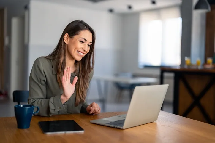 woman on a laptop waving hand speaking to a client